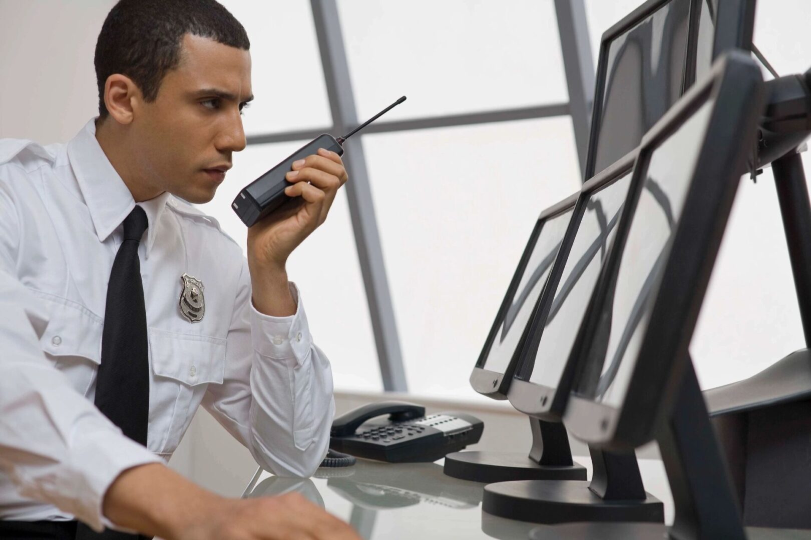 A man sitting at his desk talking on the walkie talkie.